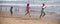 Sporty family father, mother and baby son jogging, child run by water pool along sea surf on black sand beach. Travel