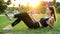 Sporty female blogger taking video selfie on mobile phone for blog, lying on the grass in city park on sunset, have a