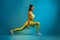 Sporty Female Doing Deep Lunge Exercise Holding Dumbbells, Blue Background