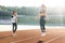 Sporty female with a good figure jumps rope on sports track of stadium. Athletic woman with personal trainer jumping