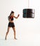 Sporty female training in stylish sportswear with punching bag in studio. Women`s sport fighting workout