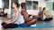 Sporty females and males meditating in yoga position Padmasana in pairs during training at gym