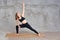 Sporty fit active yogi young woman in sportswear doing side plank pose on wooden floor mat in gym studio, female healthy girl