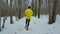 Sporty fit man running in forest on snow covered path on winter day