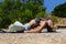 Sporty fit middle aged woman, in Corpse Pose Savasana on the bricks under her back on tropical beach