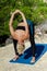 Sporty fit middle aged woman in sports wear, stretching and training on tropical beach. Female yoga instructor working out. Outdoo