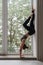 Sporty fit woman doing handstand against window