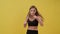 Sporty girl doing boxing exercises, making direct hit. Yellow background