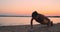 Sporty girl doing push ups on beach at sunrise. Young fit tanned smiling girl in sport top and leggings doing push ups