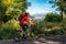 Sporty girl on mountain bike biking on road in forest with big hill at background