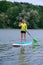 Sporty girl rowing on a SUP board on a big river and enjoy life. Stand on the paddle boarding house - amazing outdoor activities.