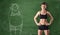 Sporty girl with slim body and picture of fat woman drawn at green chalkboard background