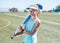 Sporty girl standing on sports field holding a blue hockey stick