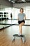 A sporty girl stands next to an exercise bench in the gym and rests after a workout. Strength and motivation