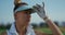 Sporty golf player stand at green course. Serious woman look distance outside.