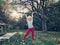 Sporty healthy strong young girl lifting wooden stick branch log in park. Cute kid playing outdoor on summer autumn fall day.