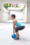 sporty hispanic woman in blue attire holding a blue kettlebell in dead lift post outdoors