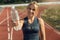 Sporty Lifestyle. Young woman on stadium standing on track with bottle of water close-up smiling cheerful blurred