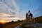 Sporty man and girl riding bikes on green hills.