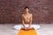 Sporty man practicing hatha yoga in studio. Male in white pants meditating and holding his foots on yellow mat. concept with copy