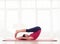 Sporty mature lady practising halasana or plow pose keeping feet