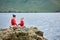 Sporty mother and daughter doing yoga on the rock near beautiful river.