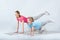 Sporty mother and daughter exercising on mats together on white