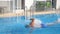 Sporty muscular man swimming in pool. Young guy floating across the basin of hotel on sunny day. Summer vacation or