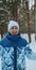 A sporty pensioner looks at the camera while walking through a winter forest