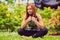 Sporty redhead female relaxing in outdoor summer park.