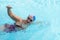 Sporty senior woman in activity swimming in the outdoor turquoise swimming pool.  With swimming cap and goggles. Healthy lifestyle