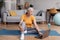 Sporty senior woman watching online sports course on laptop before domestic workout, sitting on yoga mat