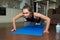 Sporty skinny girl in a black workout tight suit is doing knee push-ups at home