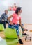 Sporty slim women taking part in gym fitness class exercising sitting on physioballs doing alternated biceps curl with