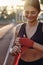 Sporty smiling girl in sportswear joyfully wrapping red boxing bandage on hand on stadium