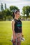 Sporty smiling girl standing on stadium green lawn with dumbbells in hands ready for exercise. Sport, physical training