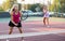 Sporty teenager girl player hitting ball with racket during friendly doubles couple match