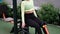 sporty woman in black and green sportswear doing sport exercises outside on sport playground. perfect healthy slim body.