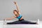 Sporty woman doing twine and stretching exercise, isolated on gray background. Beautiful girl doing yoga or pilates exercise