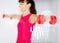 Sporty woman hands with light red dumbbells