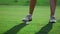 Sporty woman legs golfing at green course. Golfer train hitting ball on fairway.