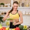 Sporty woman pouring smoothie in glass in kitchen