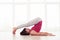 Sporty woman practicing halasana plow pose on the mat in the gym