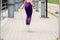 Sporty woman in purple leggings jumping with a skipping rope
