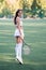 Sporty woman with rocket in a white skirt, knee socks and a top on tennis court, beautiful female tennis player in training