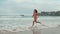 Sporty woman running along coastline in warm day. Athlete girl enjoying sea run