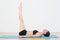 Sporty woman stretching legs upwards in fitness studio