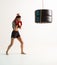 Sporty woman in stylish sportswear trains with tyres in studio on white background. Women`s sport poster