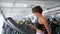 Sporty woman is training on treadmill in gym and looking in smartphone.