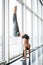 Sporty yoga girl on white background doing a handstand in pose shirshasana with entwined legs against panoramic windows